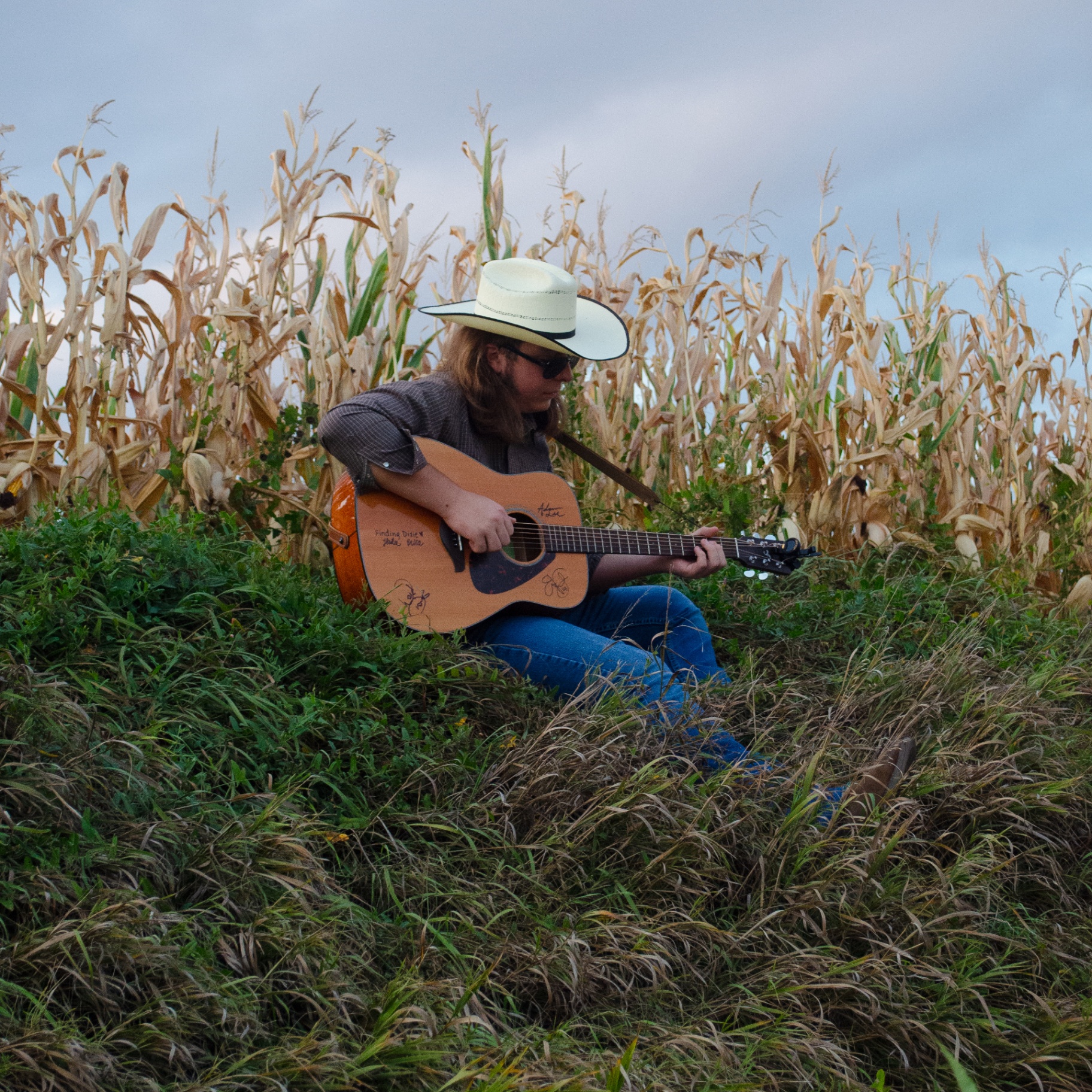 Musician with guitar beside a cornfield