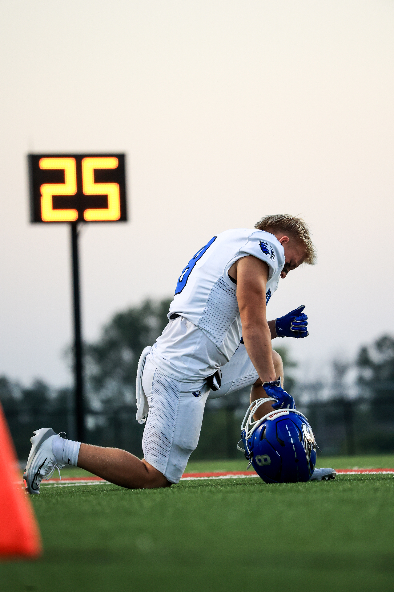Football player kneeling by play clock